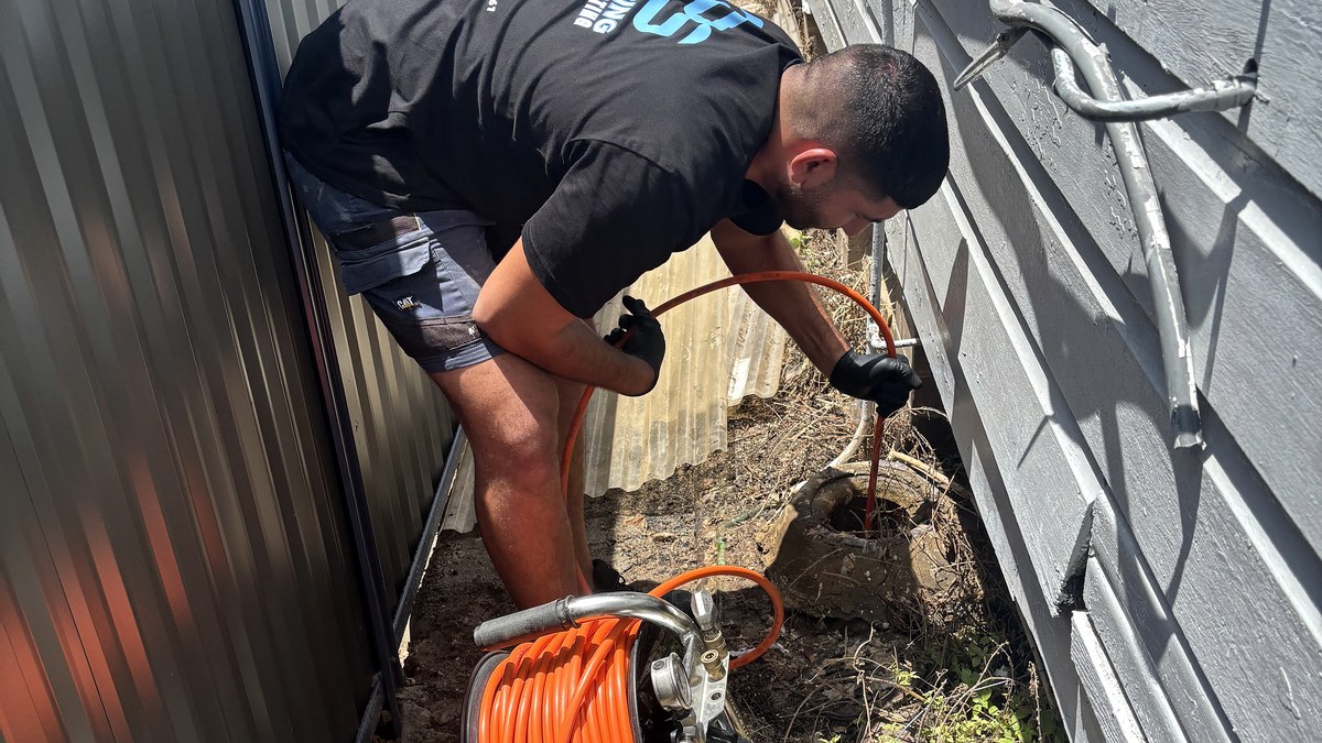 GPS technician operating high-pressure drain jetting equipment at a Sydney home